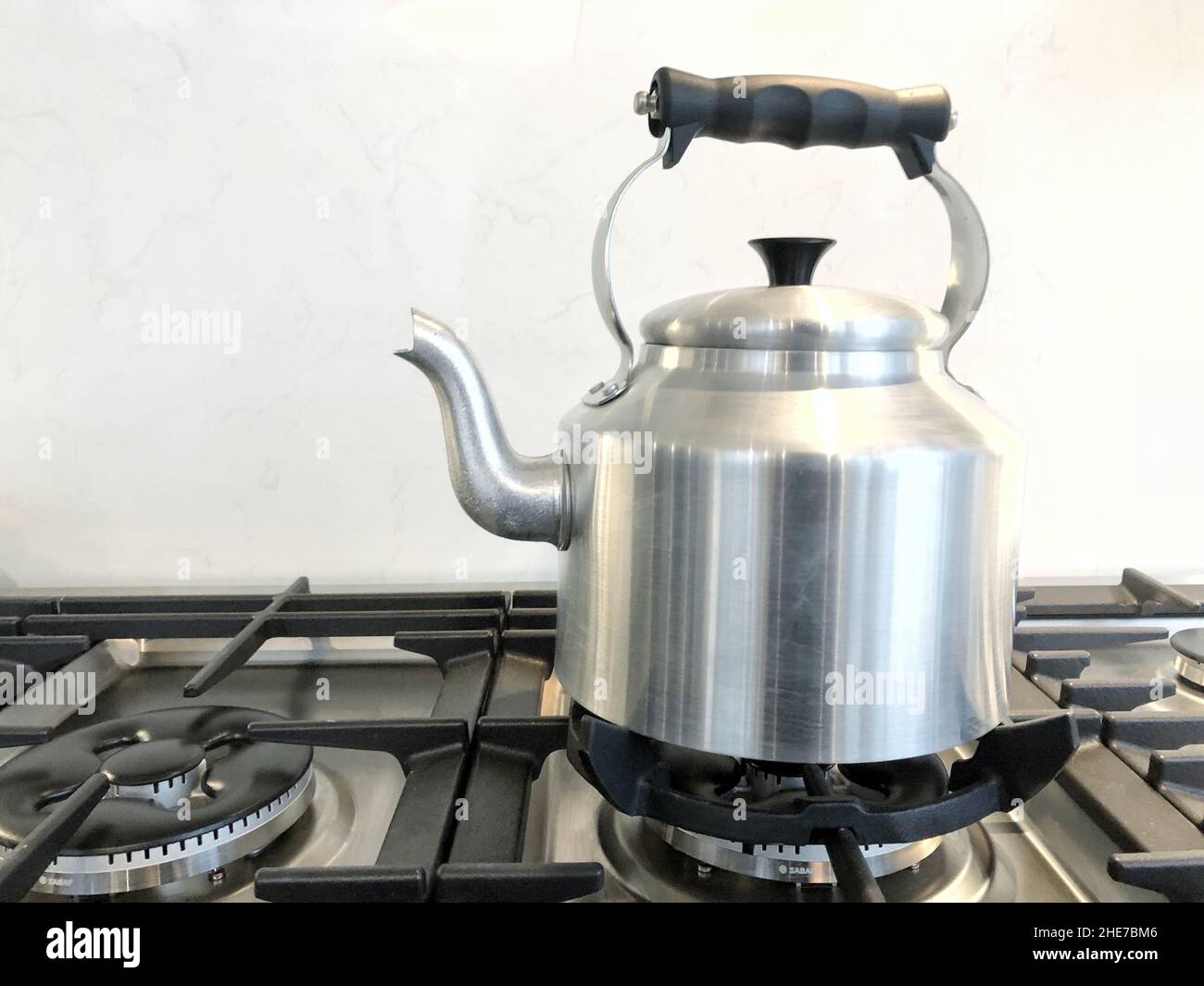 Und altmodischer silberner Wasserkocher für Teeurne mit Auslauf und kochendem Wasser auf einem Gasherd mit Kaffeekocher Stockfoto