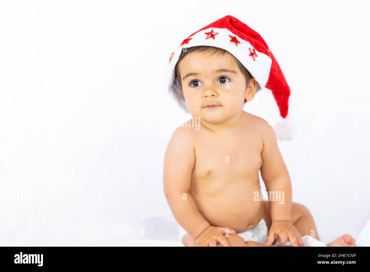Ein Junge mit einem roten Weihnachtshut auf weißem Hintergrund, Kopierraum, Porträt des Kindes mit dem Weihnachtsmann-Hut Stockfoto