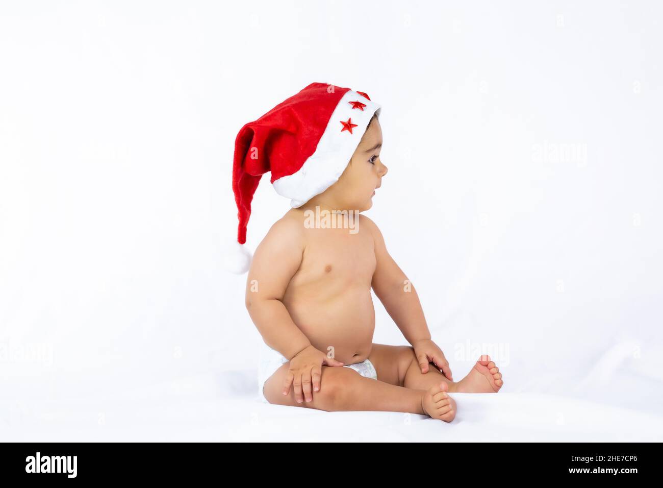 Ein kleiner Junge mit einem roten weihnachtshut auf weißem Hintergrund, Platz kopieren und nach rechts schauen Stockfoto