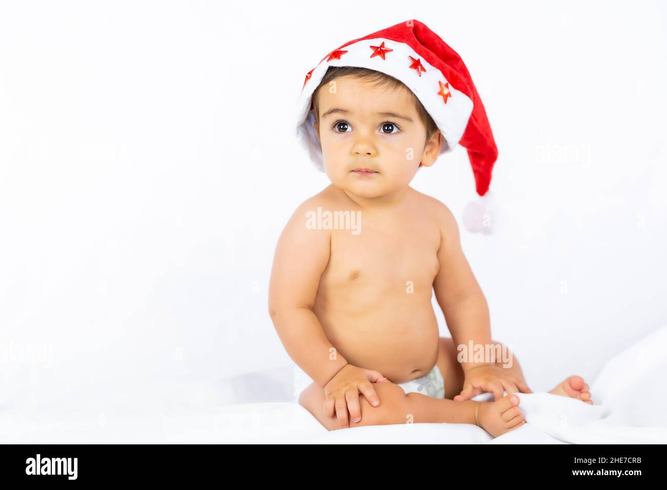Ein Junge mit einem roten Weihnachtshut auf weißem Hintergrund, Kopierraum, Porträt des Kindes mit dem Weihnachtsmann-Hut Stockfoto