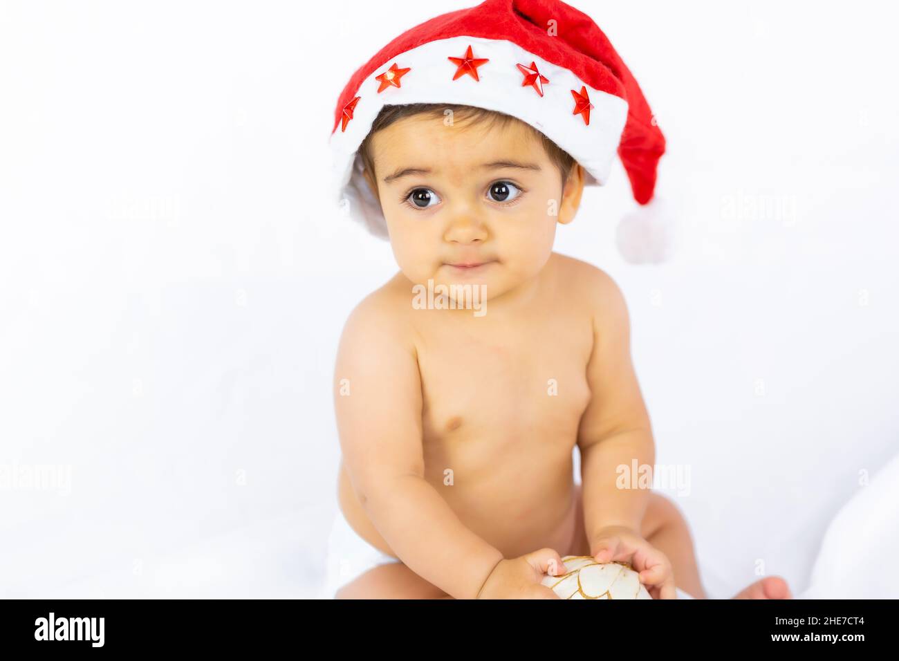 Ein Junge mit einem roten Weihnachtshut auf weißem Hintergrund, Kopierraum, Porträt des Kindes mit dem Weihnachtsmann-Hut Stockfoto