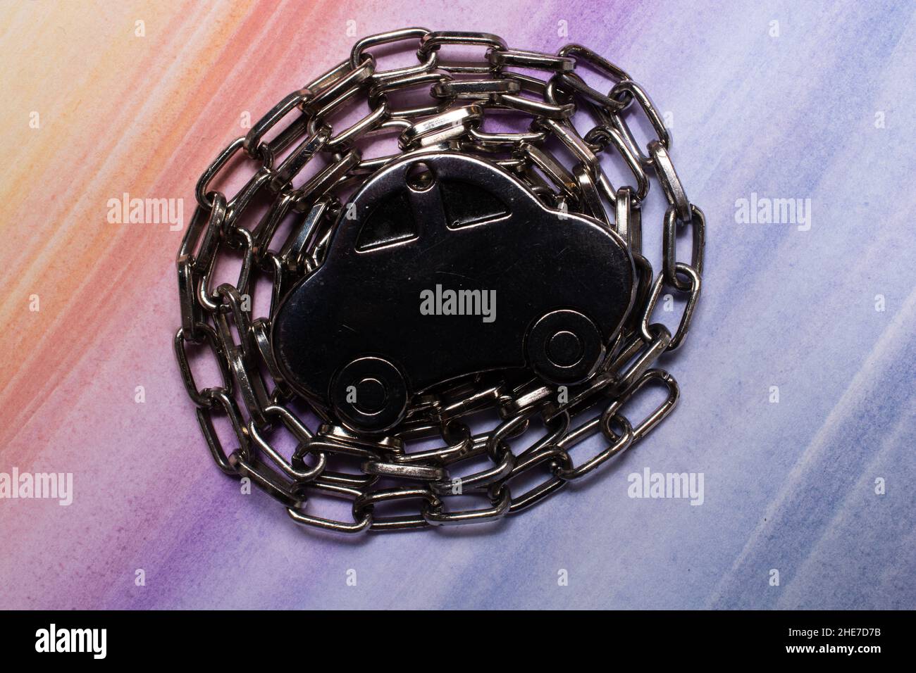 Nahaufnahme eines metallenen, autoförmigen Spielzeugs auf einer Kette auf einem farbenfrohen Hintergrund Stockfoto