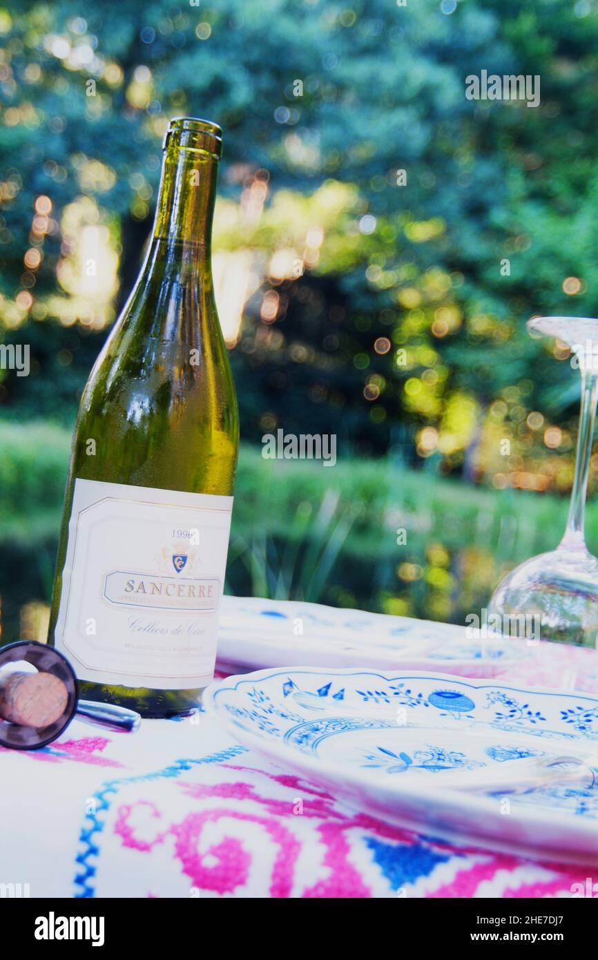Weinflasche auf dem Gartentisch, draußen im Garten | Weinflasche draußen auf einem Gartentisch Stockfoto