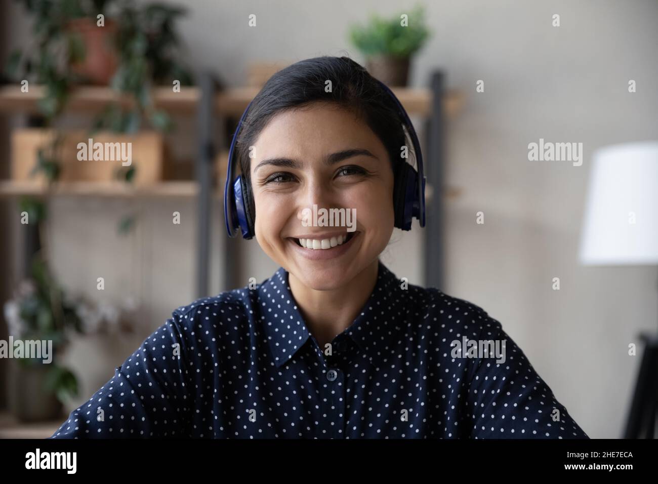 Kopfschuss einer glücklichen indischen Mitarbeiterin, einer Geschäftsfrau mit Kopfhörern Stockfoto