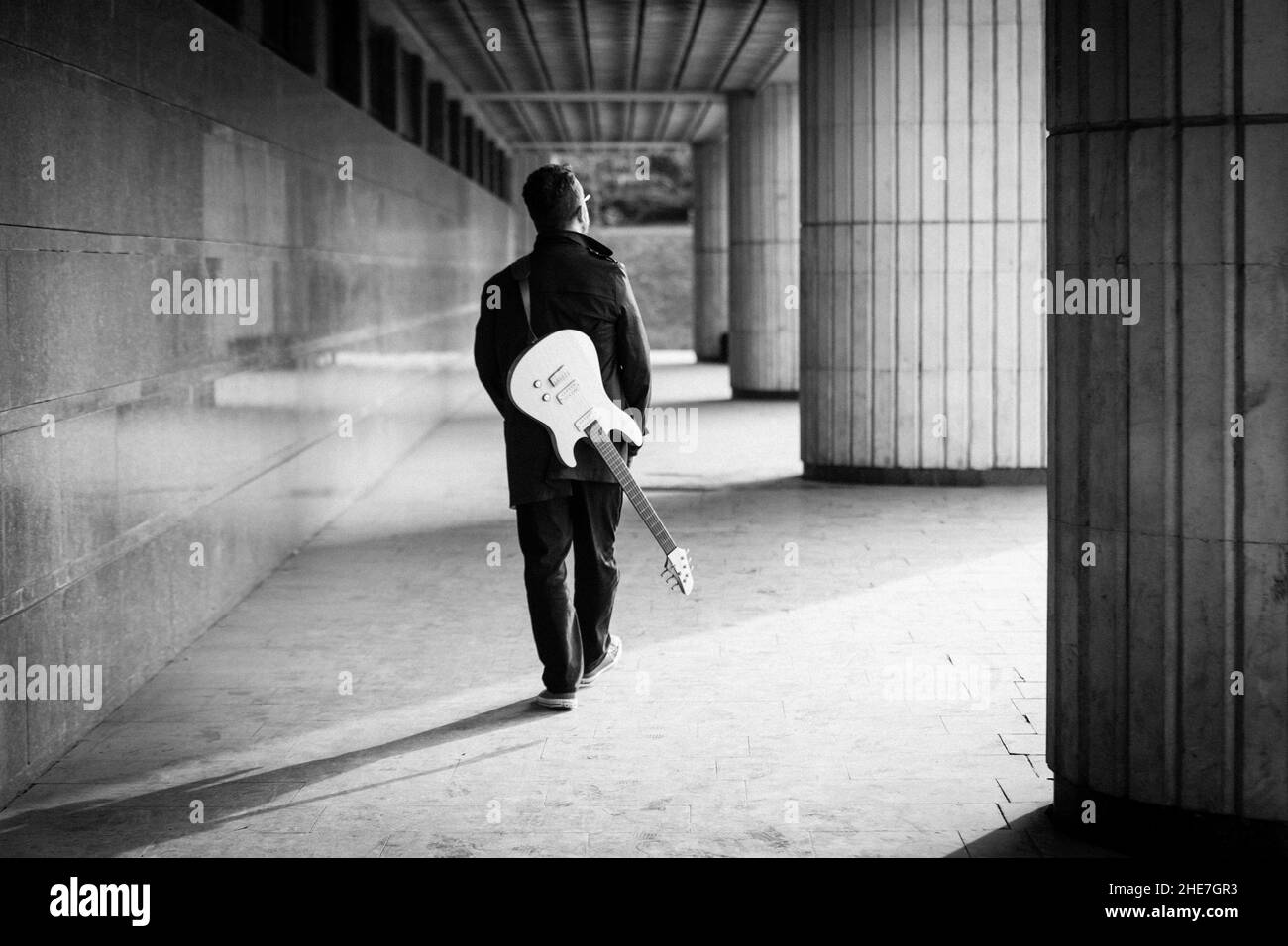 Mann in Schwarz mit Bart und E-Gitarre an städtischer Outdoor-Location. Gitarre, Solo und Street Music Konzept Stockfoto