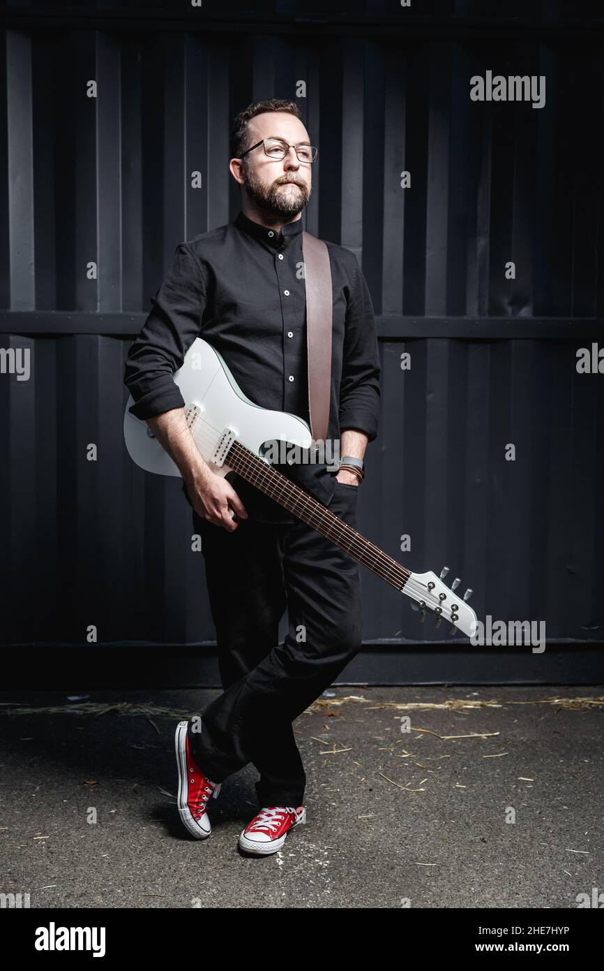 Porträt eines männlichen Gitarristen mit E-Gitarre in schwarzer Kleidung. Rockmusiker Charakter Konzept Stockfoto