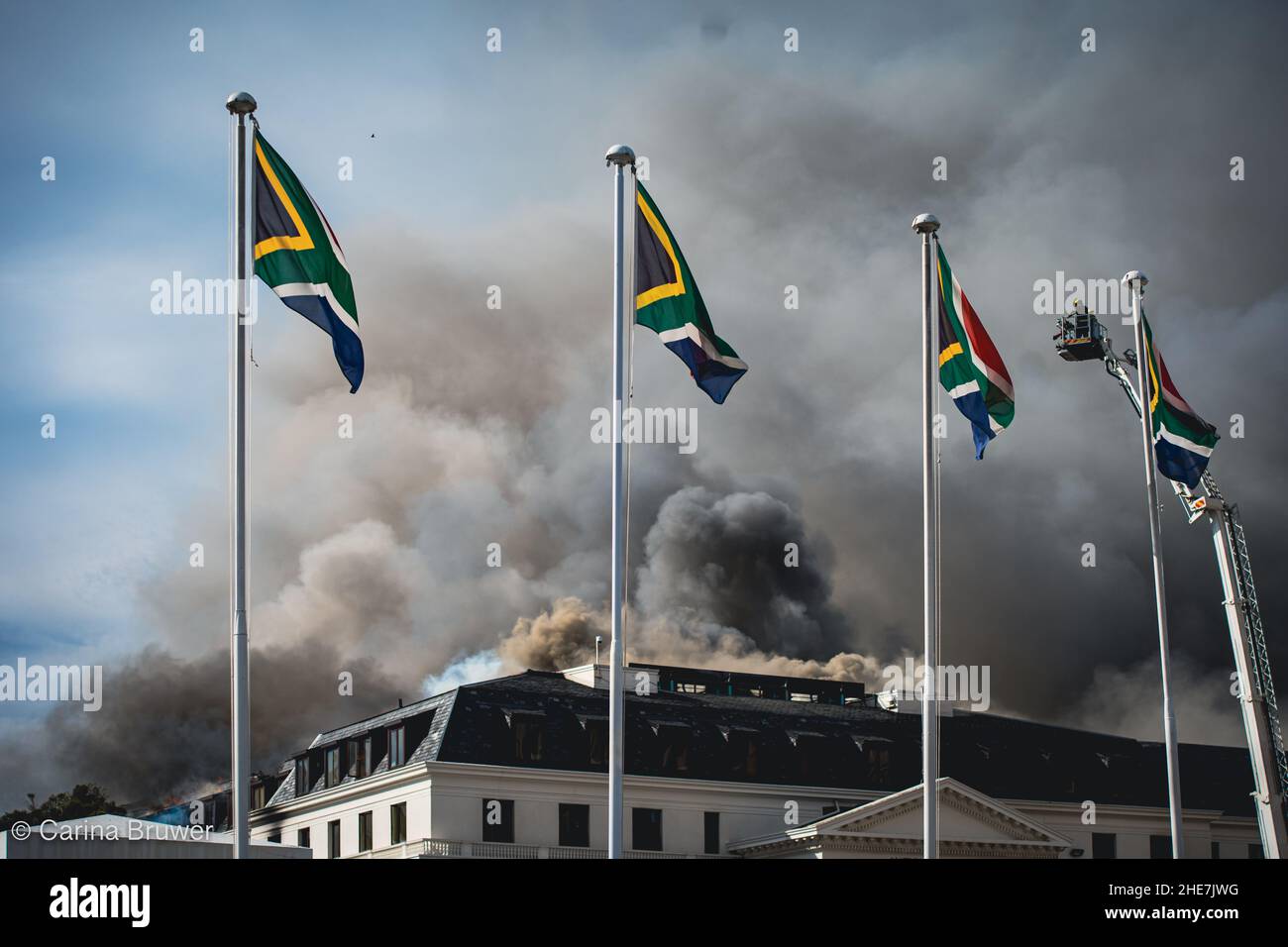 Kapstadt, Südafrika, 01-03-2022: Das südafrikanische Parlament brennt am zweiten Tag. Vier Nationalflaggen fliegen vor dem Feuer Stockfoto