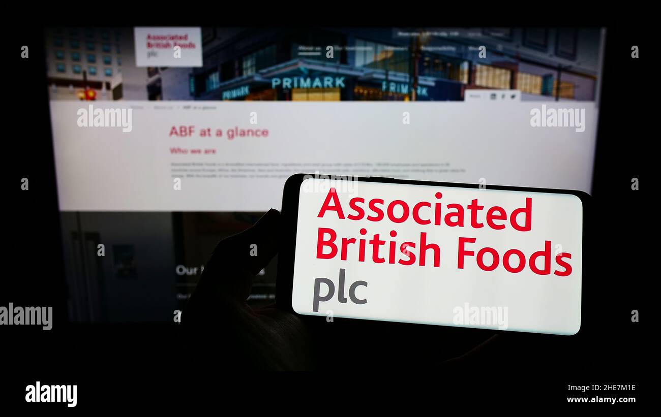 Person, die das Smartphone mit dem Logo der Associated British Foods plc (ABF) auf dem Bildschirm vor der Website hält. Konzentrieren Sie sich auf die Telefonanzeige. Stockfoto