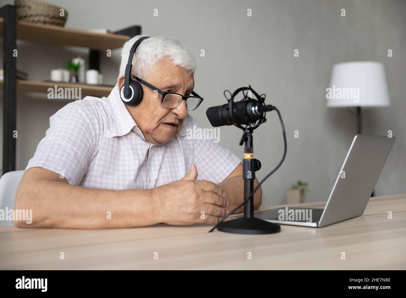 Fokussierter, reifer Mann im Ruhestand, der Stimme aufzeichnete und zu Hause vlogging. Stockfoto