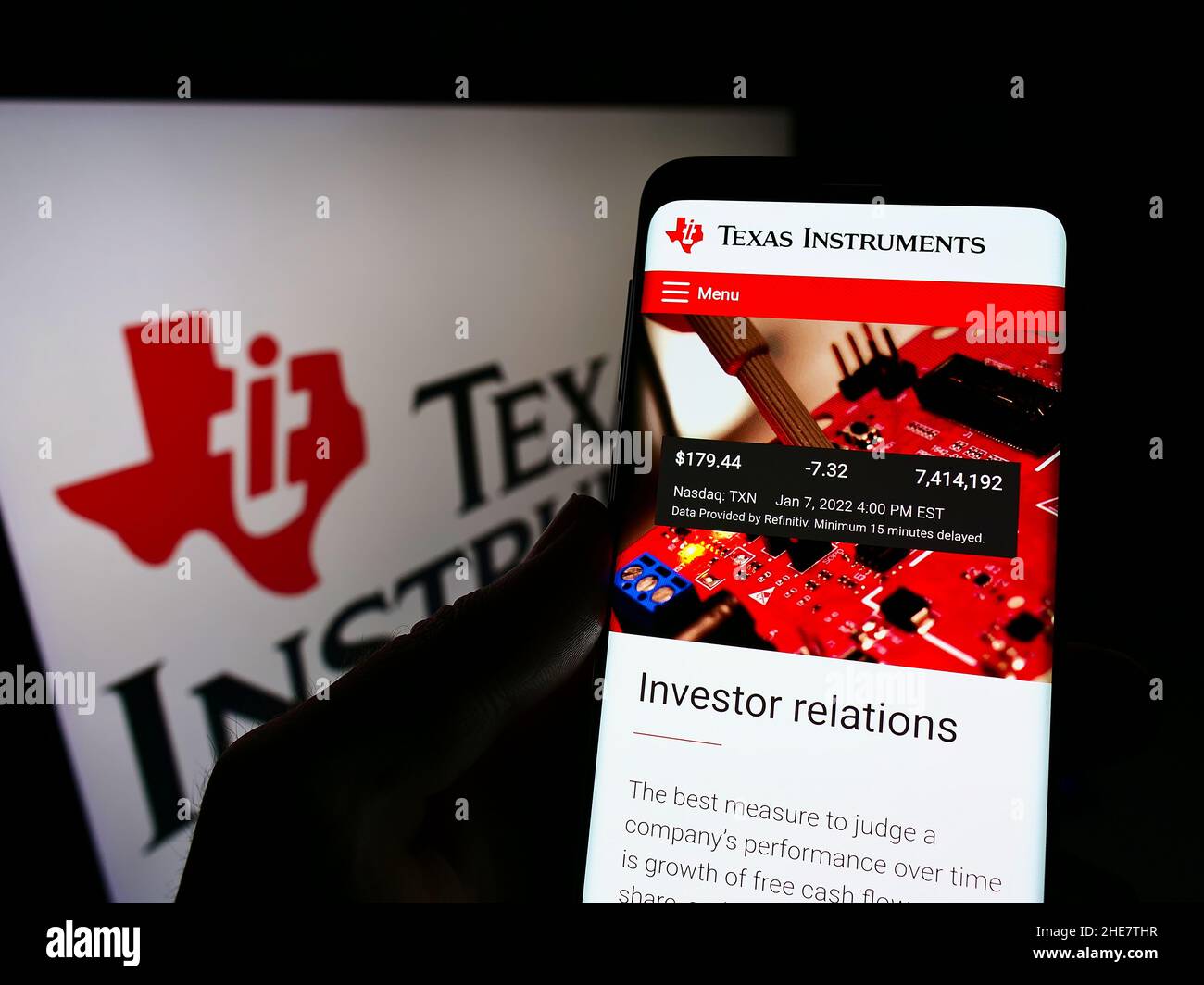 Person mit Mobiltelefon und Webseite des US-Unternehmens Texas Instruments Incorporated (TI) auf dem Bildschirm mit Logo. Konzentrieren Sie sich auf die Mitte des Telefondisplays. Stockfoto