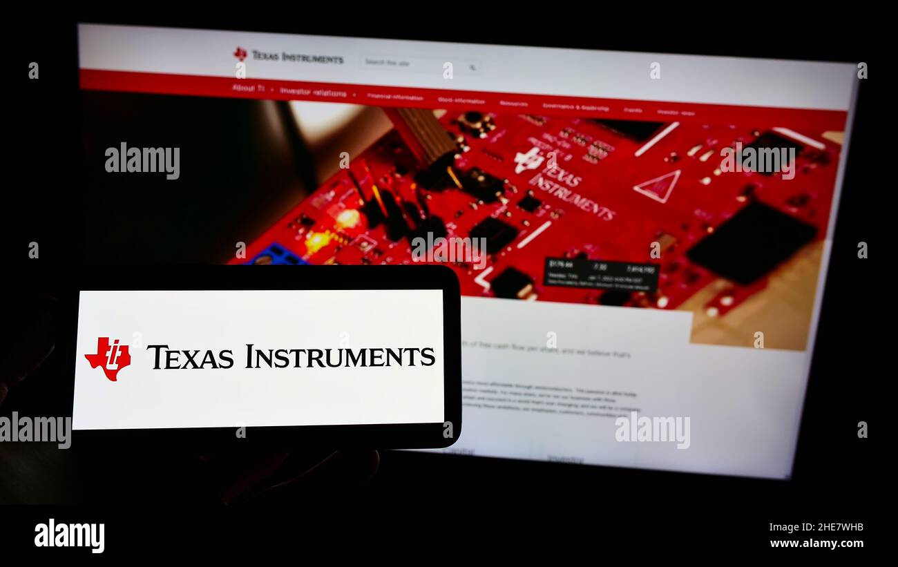 Person, die das Smartphone mit dem Logo des US-amerikanischen Unternehmens Texas Instruments Incorporated (TI) auf dem Bildschirm vor der Website hält. Konzentrieren Sie sich auf die Telefonanzeige. Stockfoto