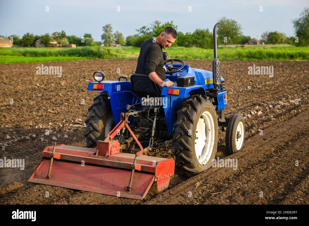 Cherson Oblast, Ukraine - 29. Mai 2021: Seniorbauer arbeitet auf dem Feld auf einem Traktor. Saisonarbeiter. Lockern, Anbau. Pflügen. Einstellung eines Stockfoto