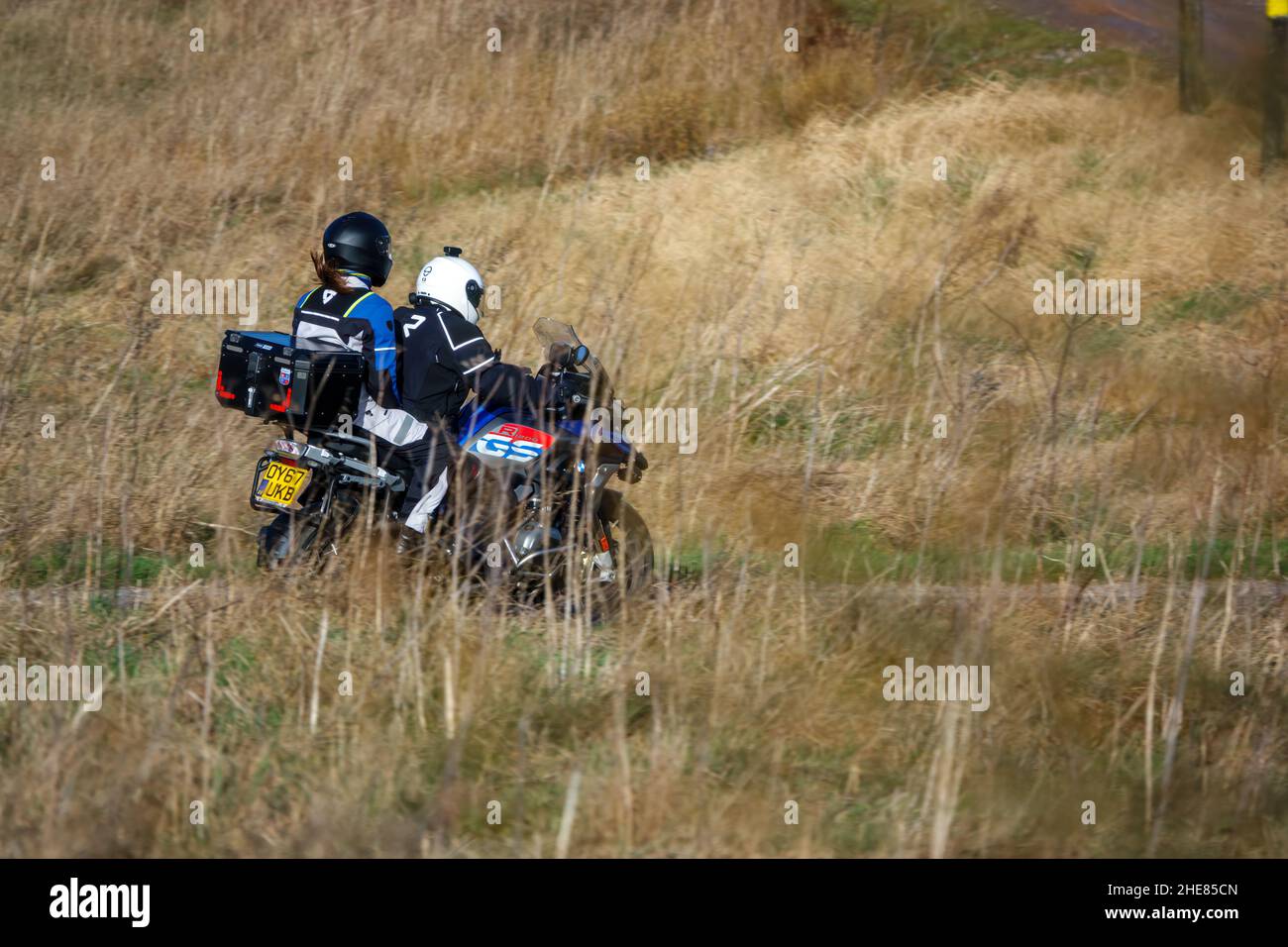 Motorradfahrer und Sozius auf einem BMW R1200 GS Motorrad, das durch die Winterlandschaft fährt Stockfoto