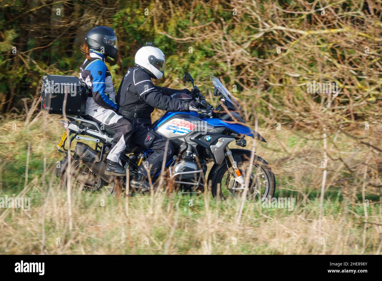 Motorradfahrer und Sozius auf einem BMW R1200 GS Motorrad, das durch die Winterlandschaft fährt Stockfoto