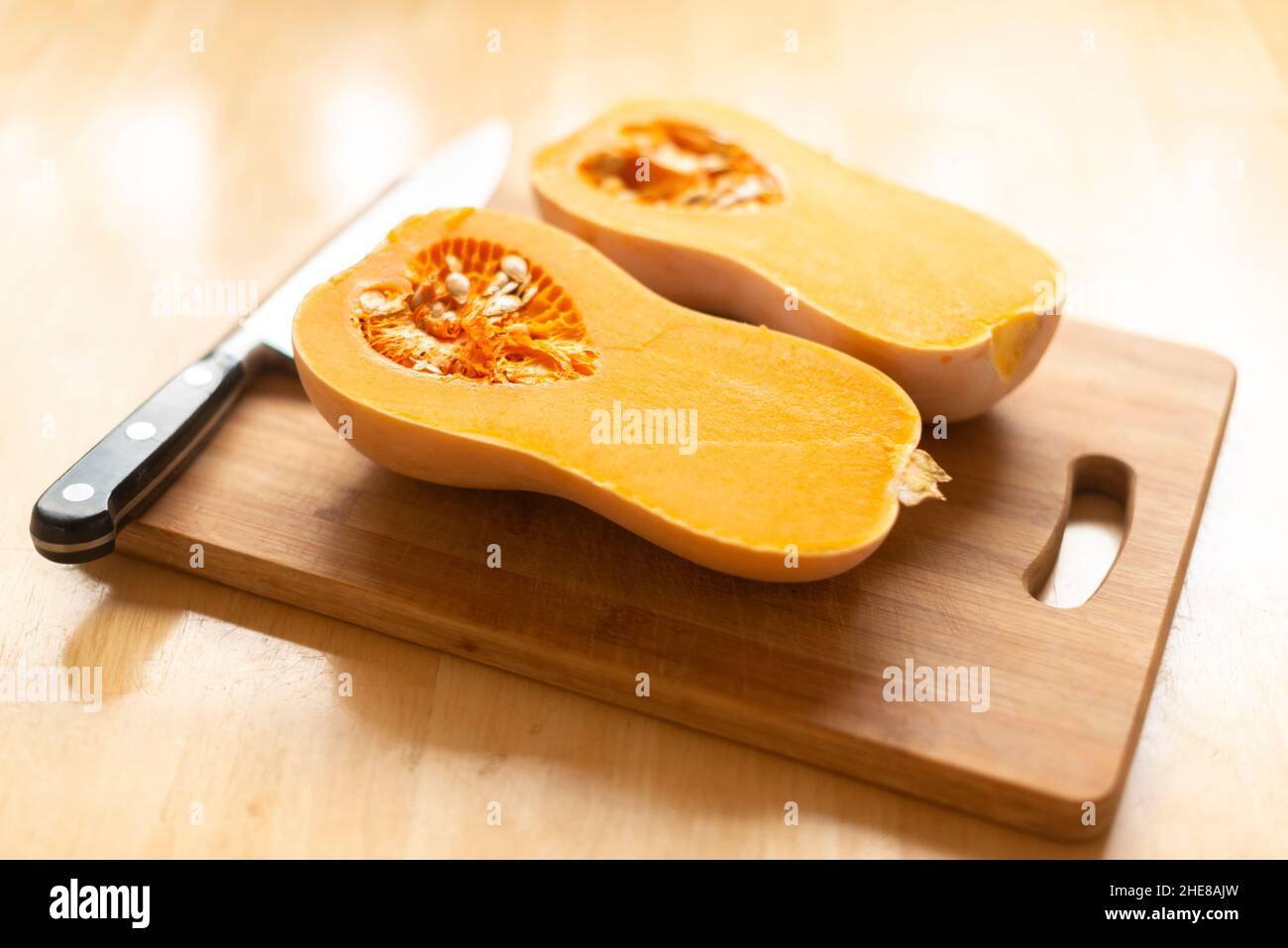 Butternut Squash (Cucurbita moschata)-mcut in zwei Hälften auf einem Schneidebrett-selektiven Fokus Stockfoto