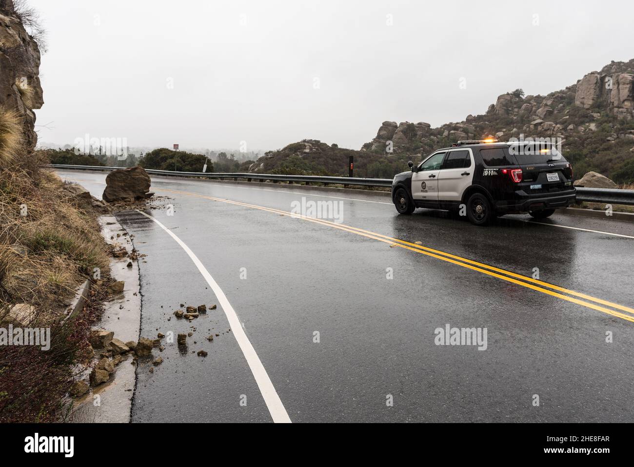 Los Angeles, Kalifornien, USA - 30. Dezember 2021: Polizeiauto von Los Angeles beobachtet einen kleinen regen Erdrutsch auf der Santa Susana Pass Road. Stockfoto