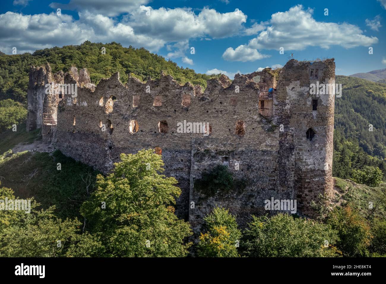 Luftaufnahme der unter Restaurierung mittelalterlichen Sasovsky Burg über dem Fluss Hron (Garam) in der Slowakei mit kreisförmigem Torturm, ruiniert gotischen Palast blau Stockfoto