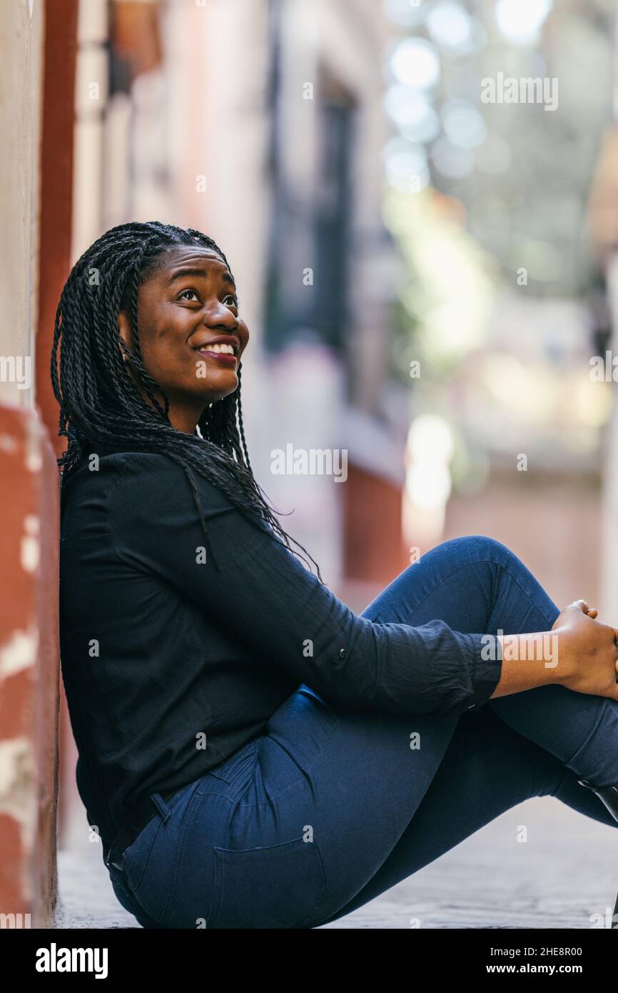 Afrikanische Frau, die auf der Straße sitzt und aufschaut Stockfoto