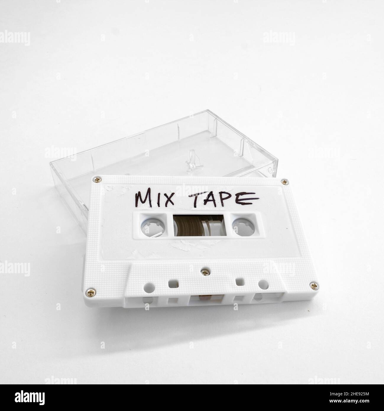 Weißes Kassettenband mit den Wörtern, DIE IN handgeschriebenen Buchstaben geschrieben sind und auf einem durchsichtigen Kassettengehäuse aus Kunststoff liegen. Stockfoto