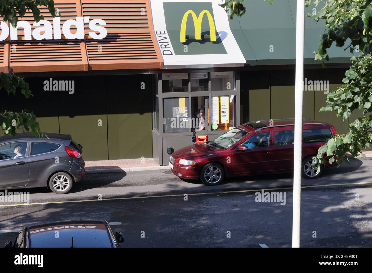 Autos in der Schlange, die auf McDonalds warten, fahren durch den Service. England Stockfoto