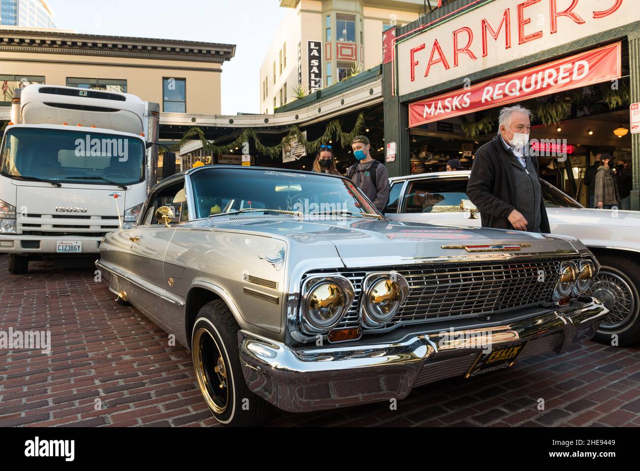 Seattle, USA. 9 Januar 2022. Eine Lowrider-Gruppe taetup auf dem Pike Place Market, während Touristen und Einheimische spät am Tag Fotos machen. Oldtimer-Gruppen nutzen den Mangel an Menschen in der Innenstadt, um ihre Oldtimer durch die Stadt zu fahren und Fotos zu machen. Quelle: James Anderson/Alamy Live News Stockfoto