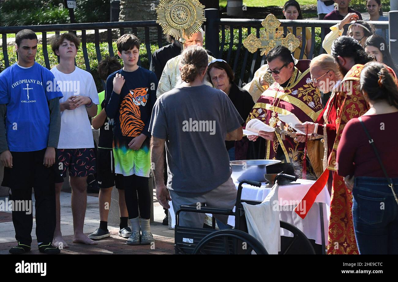 Orlando, Usa. 09th Januar 2022. Isaac Abdelmessih (links) und andere Kreuztaucher sehen sich als Fr. John Hamatie (dritte rechts) und andere Geistliche rezitieren Gebete am Lake Eola während des jährlichen Epiphany Cross Dive der St. George Orthodoxen Kirche in der Innenstadt von Orlando. Die Feier ehrt die Taufe Jesu Christi und es heißt, dass die Person, die das Kreuz abholt, für den Rest des Jahres Glück erhalten wird. (Foto von Paul Hennessy/SOPA Images/Sipa USA) Quelle: SIPA USA/Alamy Live News Stockfoto