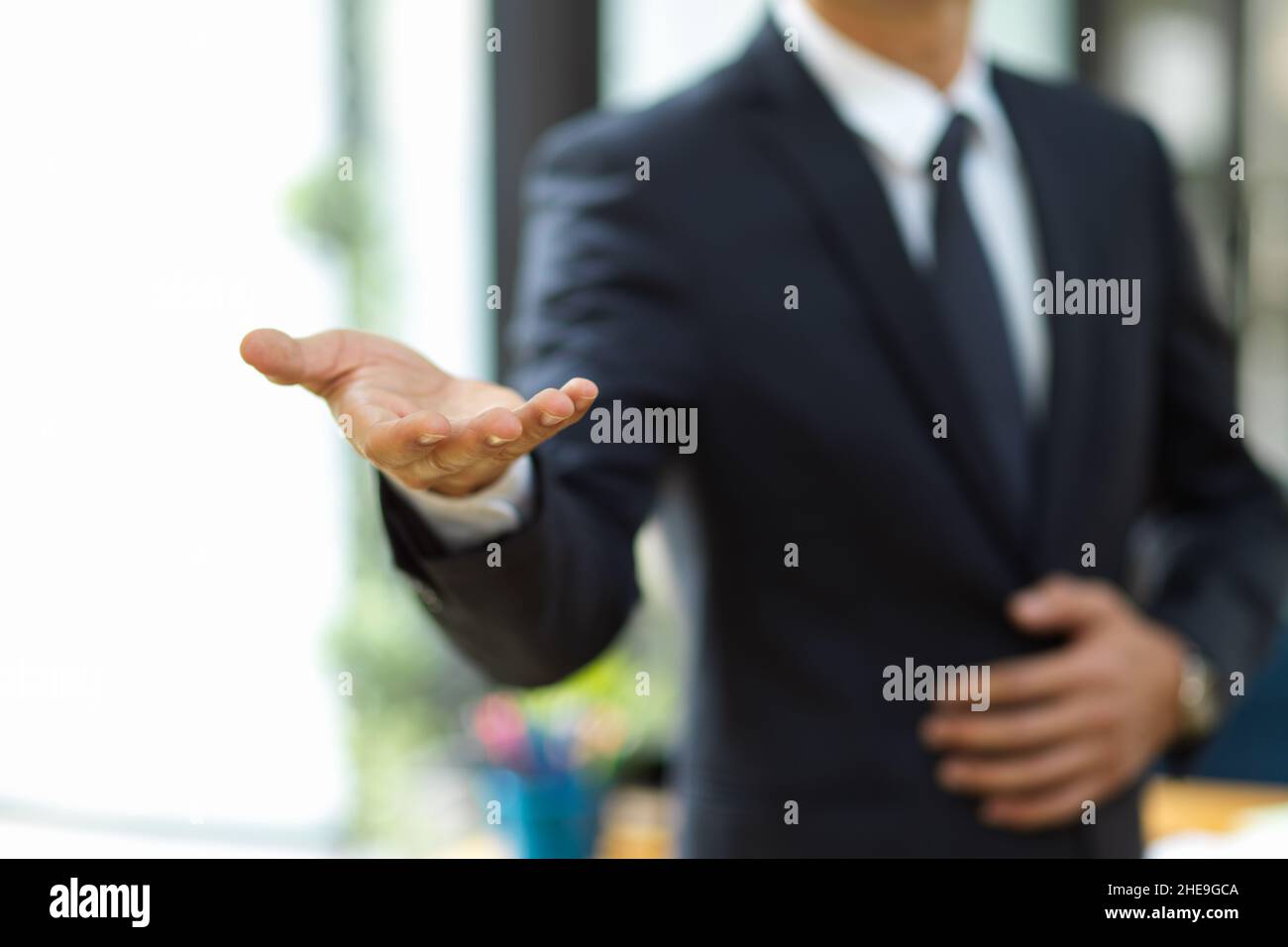 Ein Geschäftsmann in einem formellen Anzug, der die Hand ausstreckte, um die Kamera anzuhalten. Grußhand, Willkommenshand. Zugeschnittenes Bild Stockfoto
