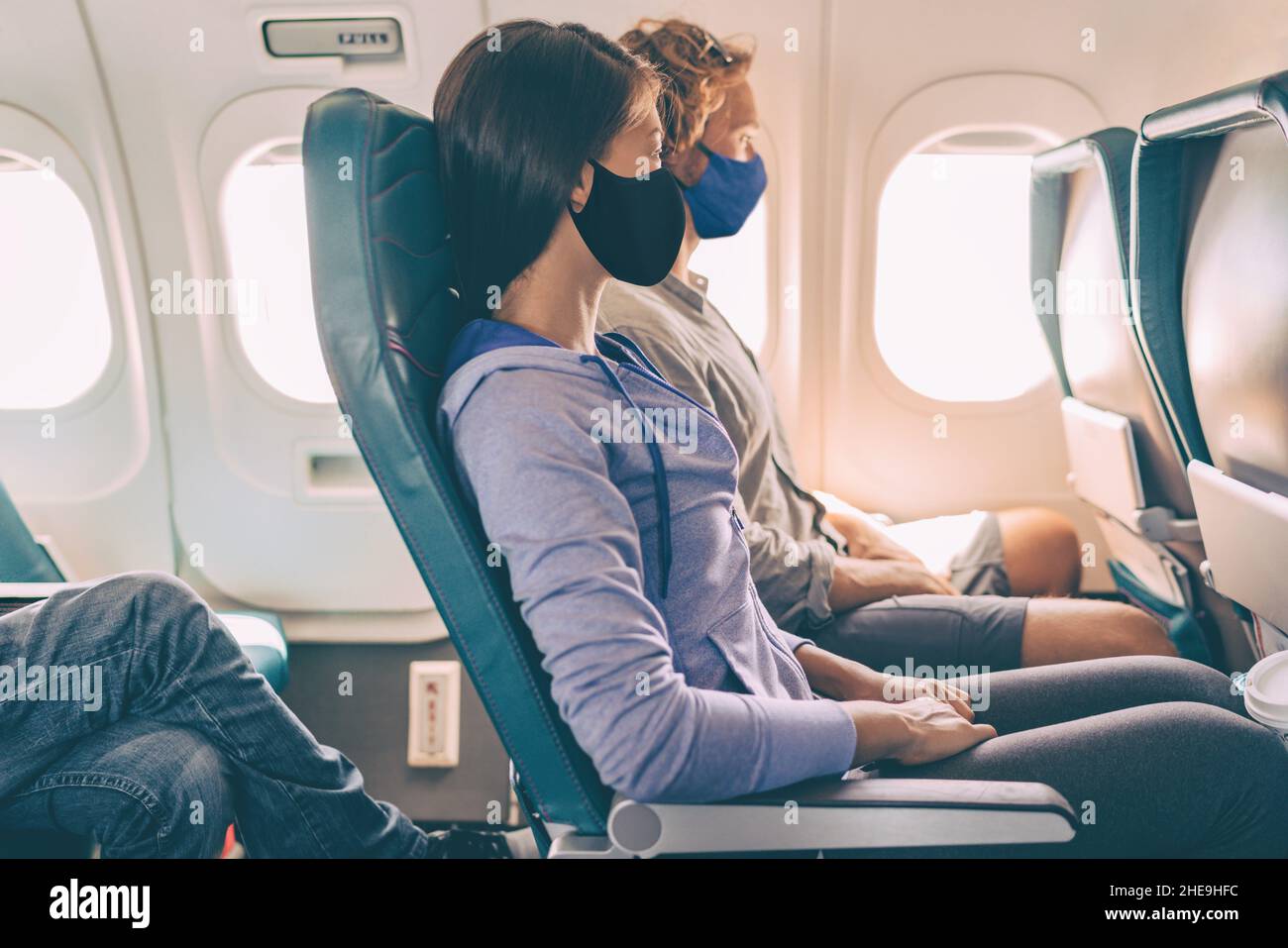 Paar Touristen mit Gesichtsmasken auf Reise Urlaub Flug im Flugzeug. Coronavirus-Sicherheitsprävention für Fluggäste. Menschen leben Stockfoto