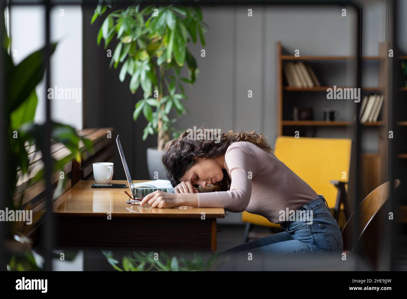 Müde Geschäftsfrau, die im Büro auf dem Schreibtisch schläft, erschöpft unmotiviert mit monotonen Aufgaben, braucht Ruhe Stockfoto