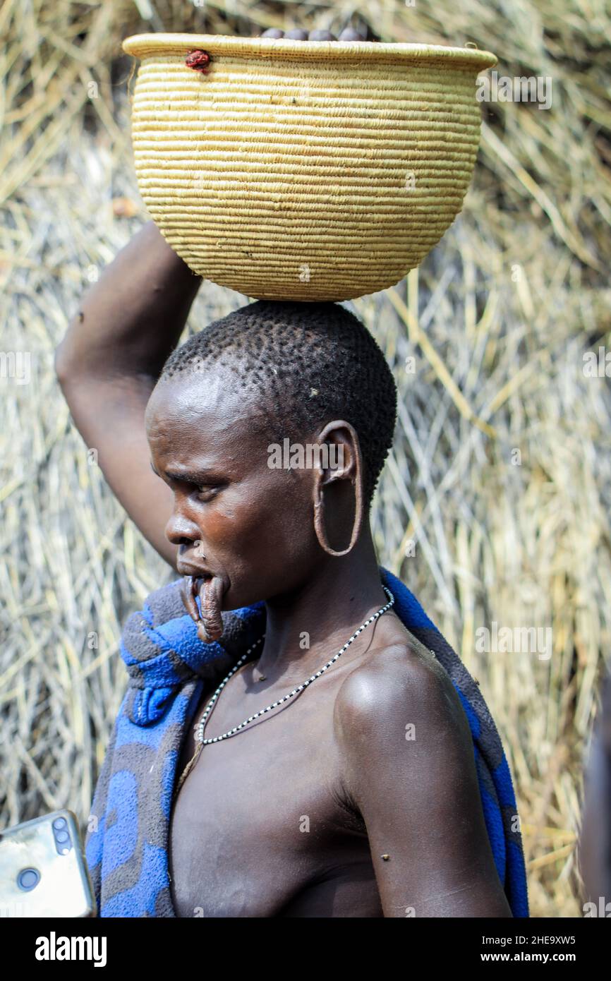 Omo River Valley, Äthiopien - 29. November 2020: Porträt einer afrikanischen Frau mit großen Löchern in den Ohren und den geschnittenen Haaren im lokalen Mursi-Stammesdorf Stockfoto