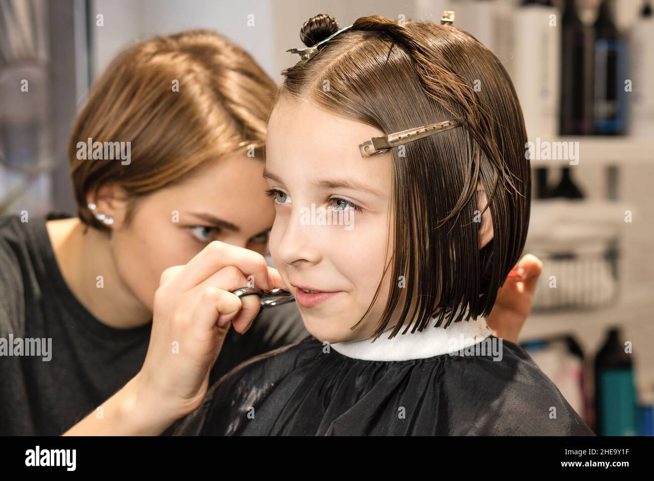 Schönheit Mode Kind Modell Bob Kurze Frisur. Kleines Mädchen Client mit kurzen Bob Haar. Friseursalon schneidet ihr die Haare. Prozess. Kurse in Friseursalon. Schönheitskonzept. Stockfoto