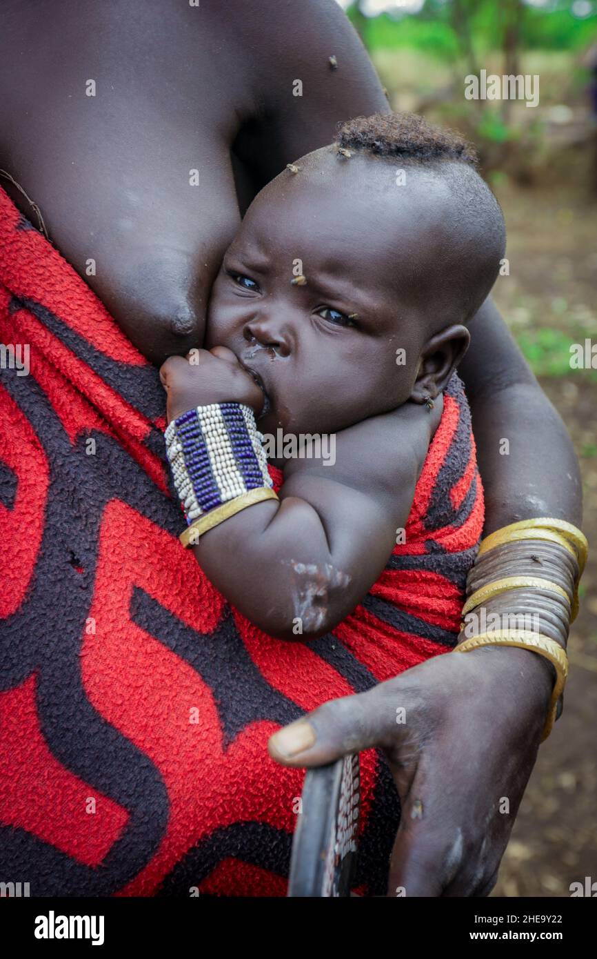 Omo River Valley, Äthiopien, November 2020, ein Kleinkind mit seiner Mutter aus dem Stamm der Mursi Stockfoto
