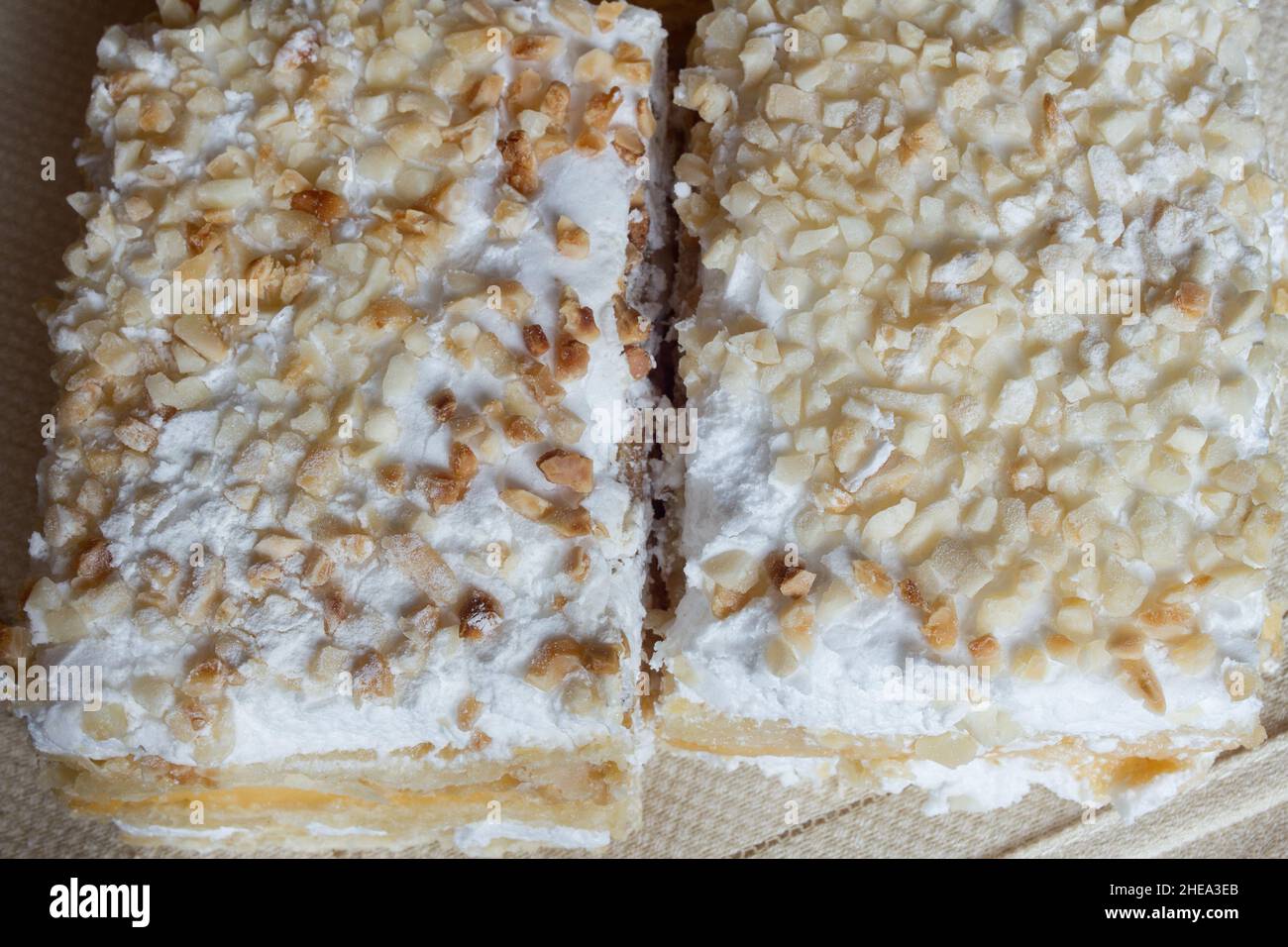 Blick von oben auf millefeuille aus Blätterteig und gefüllt mit Gebäck-Creme und Baiser gekrönt mit gerösteten gehackten Mandeln und Puderzucker auf c Stockfoto