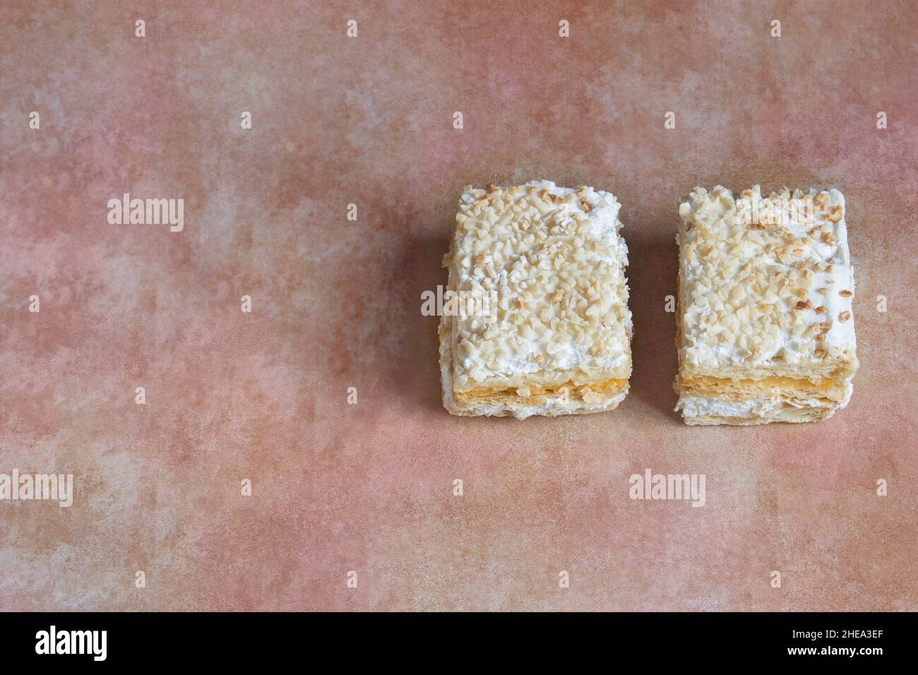 Zwei traditionelle Dessertportionen millefeuille mit Blätterteig und gefüllt mit Backcreme und Baiser mit gerösteten gehackten Mandeln und Zucker. Stockfoto