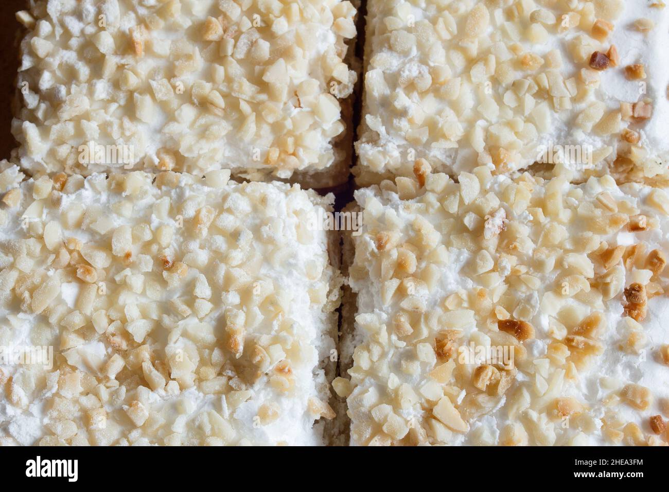 Blick von oben auf ein süßes, kreuzförmiges Dessert mit Puderzucker und gehackten Mandeln, Blätterteig, Rahm und Baiser. Traditionelle Speisen und Texturen. Stockfoto