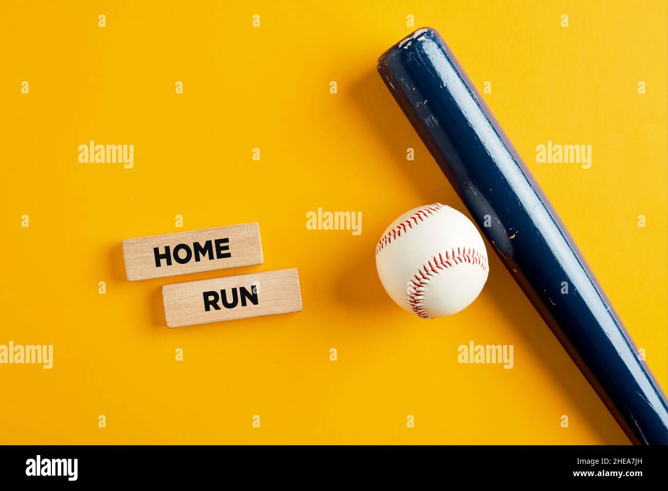 Baseballball und Schläger auf gelbem Hintergrund mit den Worten Home Run auf Holzblöcken. Stockfoto