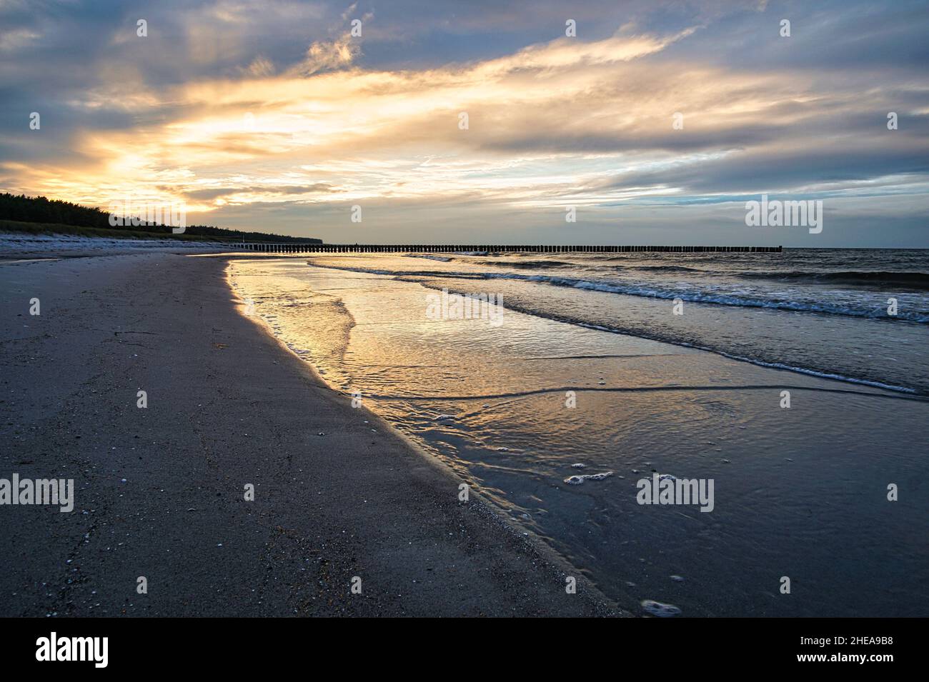 Sonnenuntergang an der ostseeküste mit Wolken am Himmel und Spiegelungen im Wasser. Dazu das Rauschen des Meeres und eine frische Brise um die Nase. Stockfoto