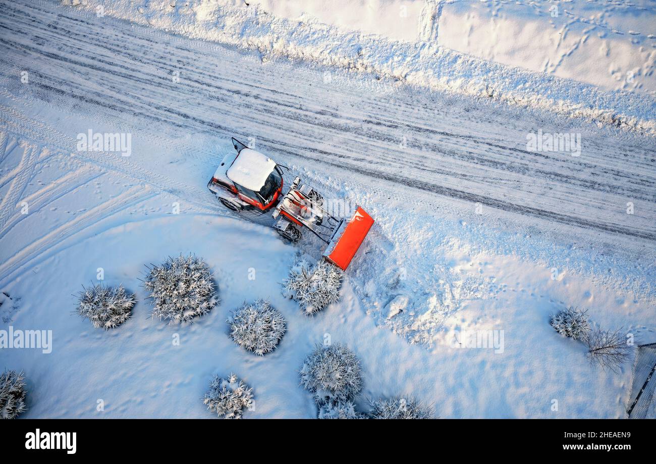 Schneeräumung mit rotem Traktor auf der Straße. SUNY Wintertag, Drone Blick von oben. Antenne. Blick von oben. Stockfoto