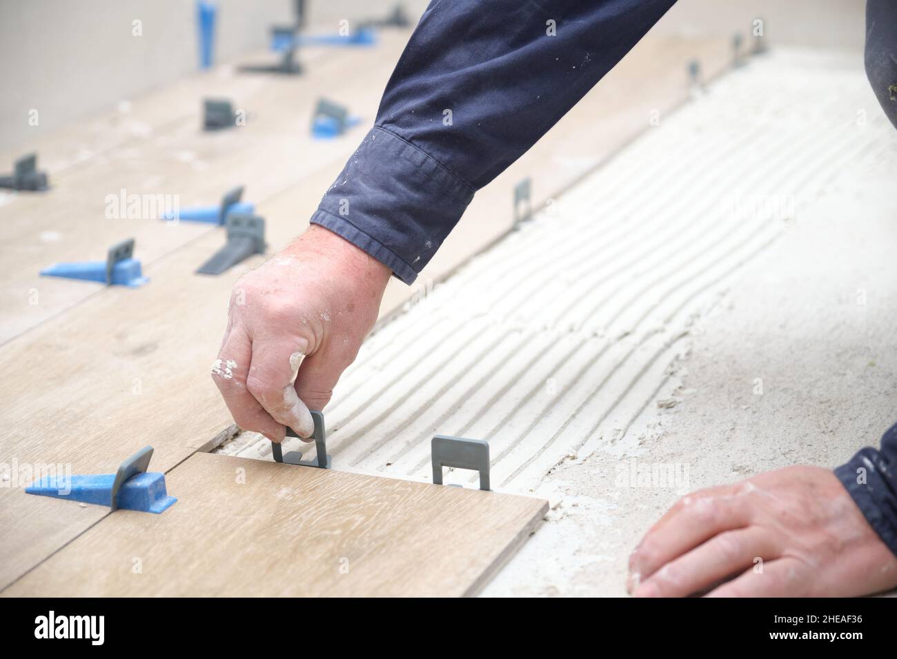 Arbeiter Hände Verlegung keramische Holz-Effekt Fliesen mit Fliesenlegern. Stockfoto