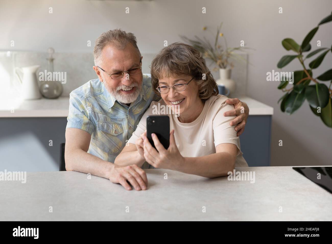 Glückliches Ehepaar mittleren Alters, das Handy benutzte. Stockfoto