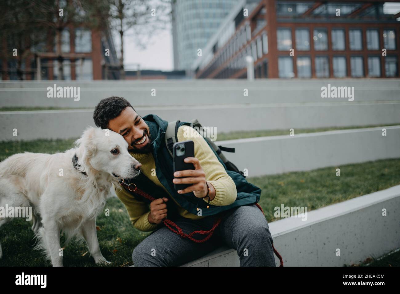 Glücklicher junger Mann, der mit seinem Hund im Freien in der Stadt Selfie macht. Stockfoto