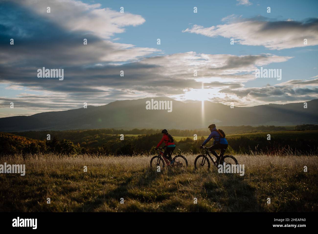 Aktives Seniorenpaar, das im Herbst in der Natur in der Dämmerung Fahrräder im Freien reitet. Stockfoto