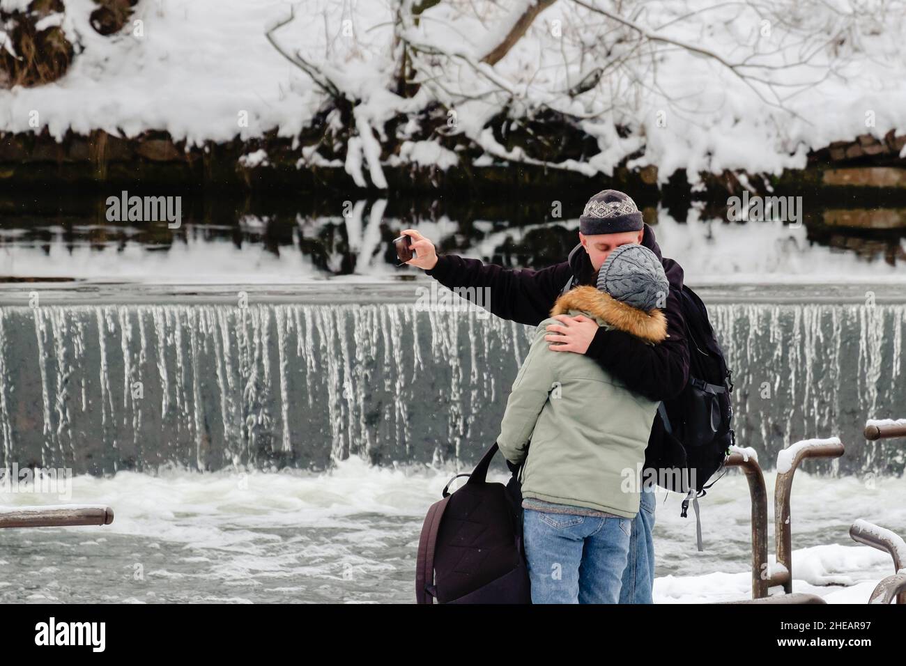 Liebe überall. Küssendes Paar, das Selfie in der Nähe eines Wasserfalls nimmt. Junger Mann und Frau zusammen. Stockfoto