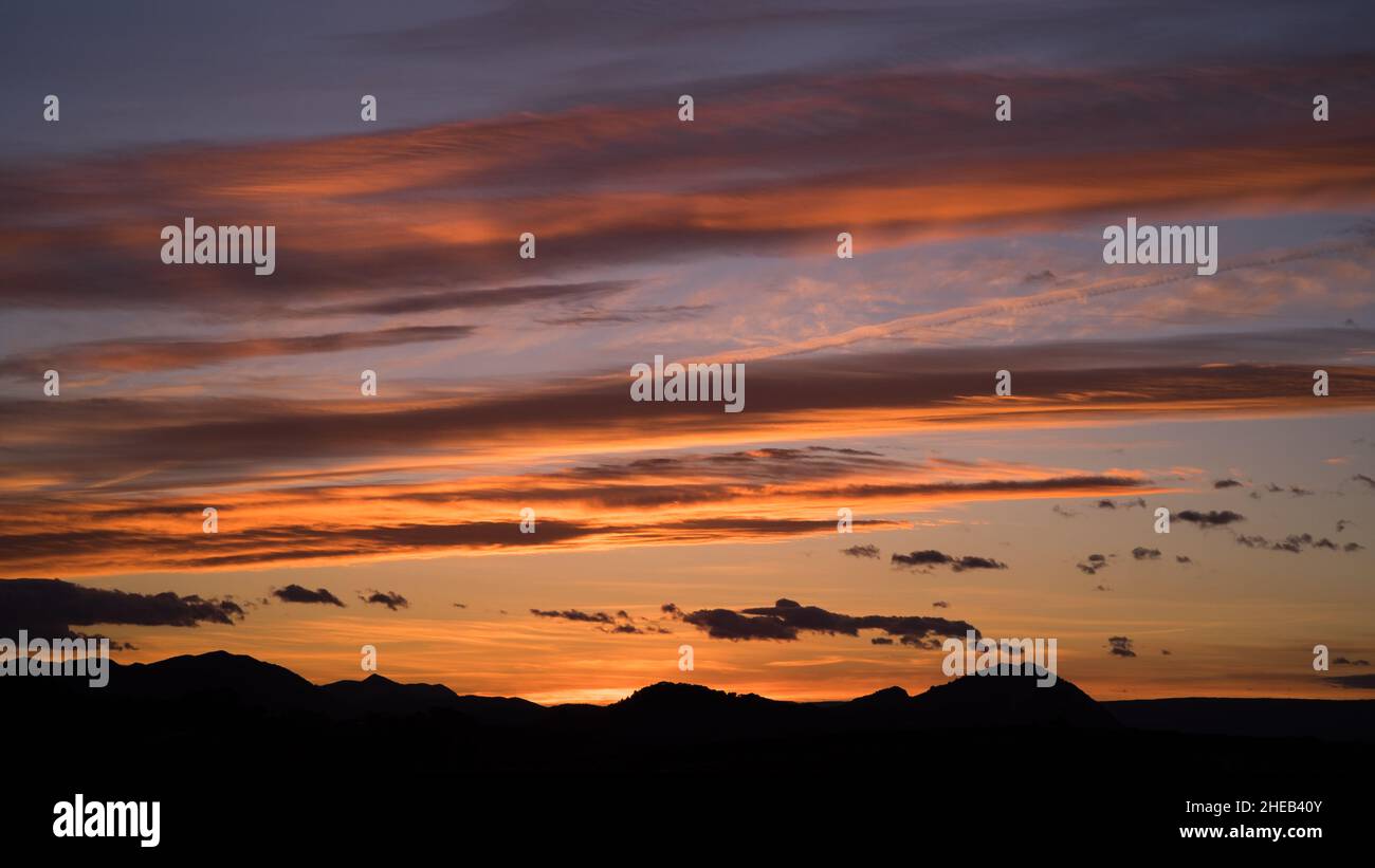 Schönes Licht und Wolken während des Sonnenuntergangs über dunklen Hügeln der Region Valenciana Stockfoto