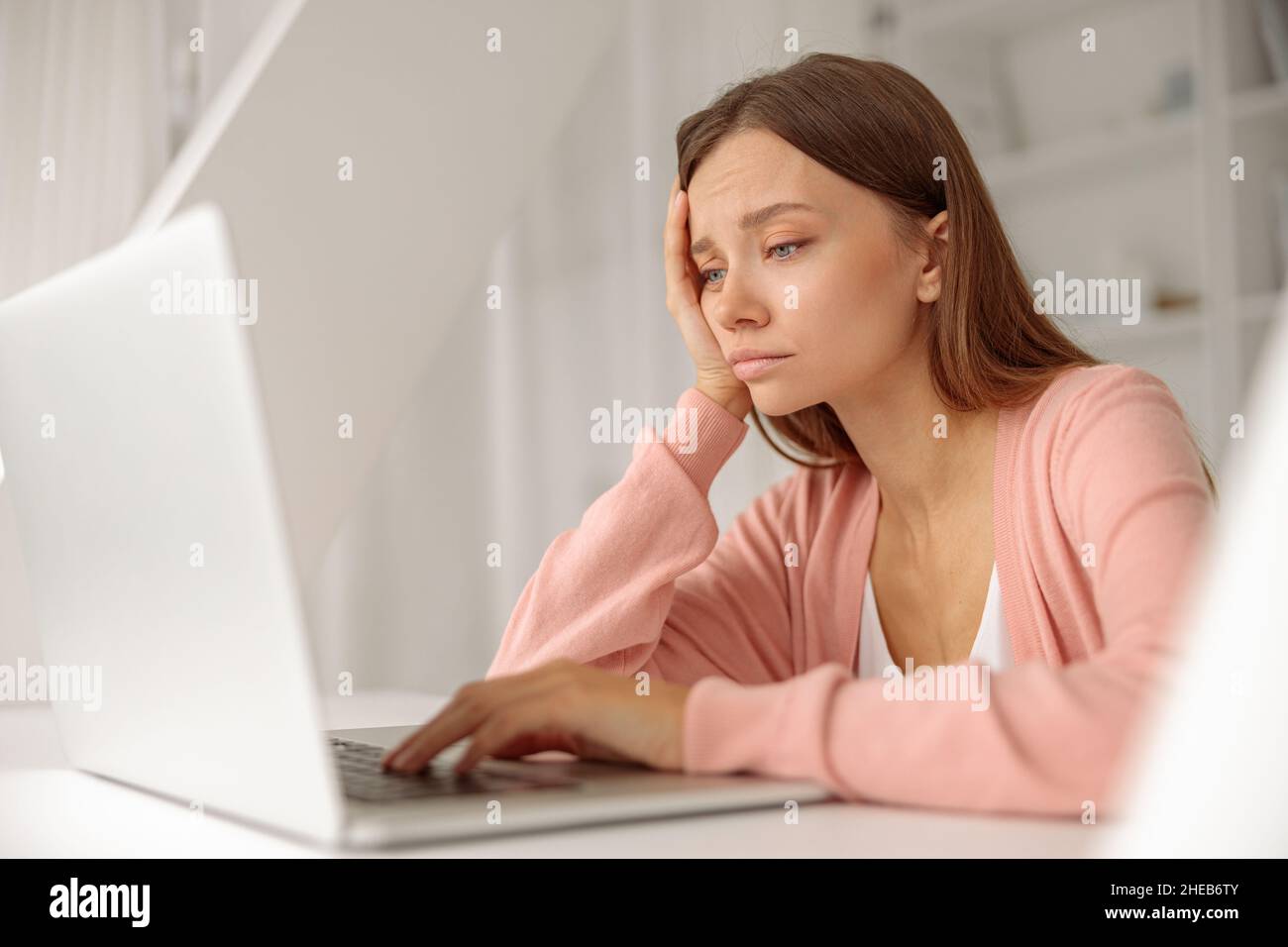 Müde Frau, die zu Hause am Laptop arbeitet Stockfoto
