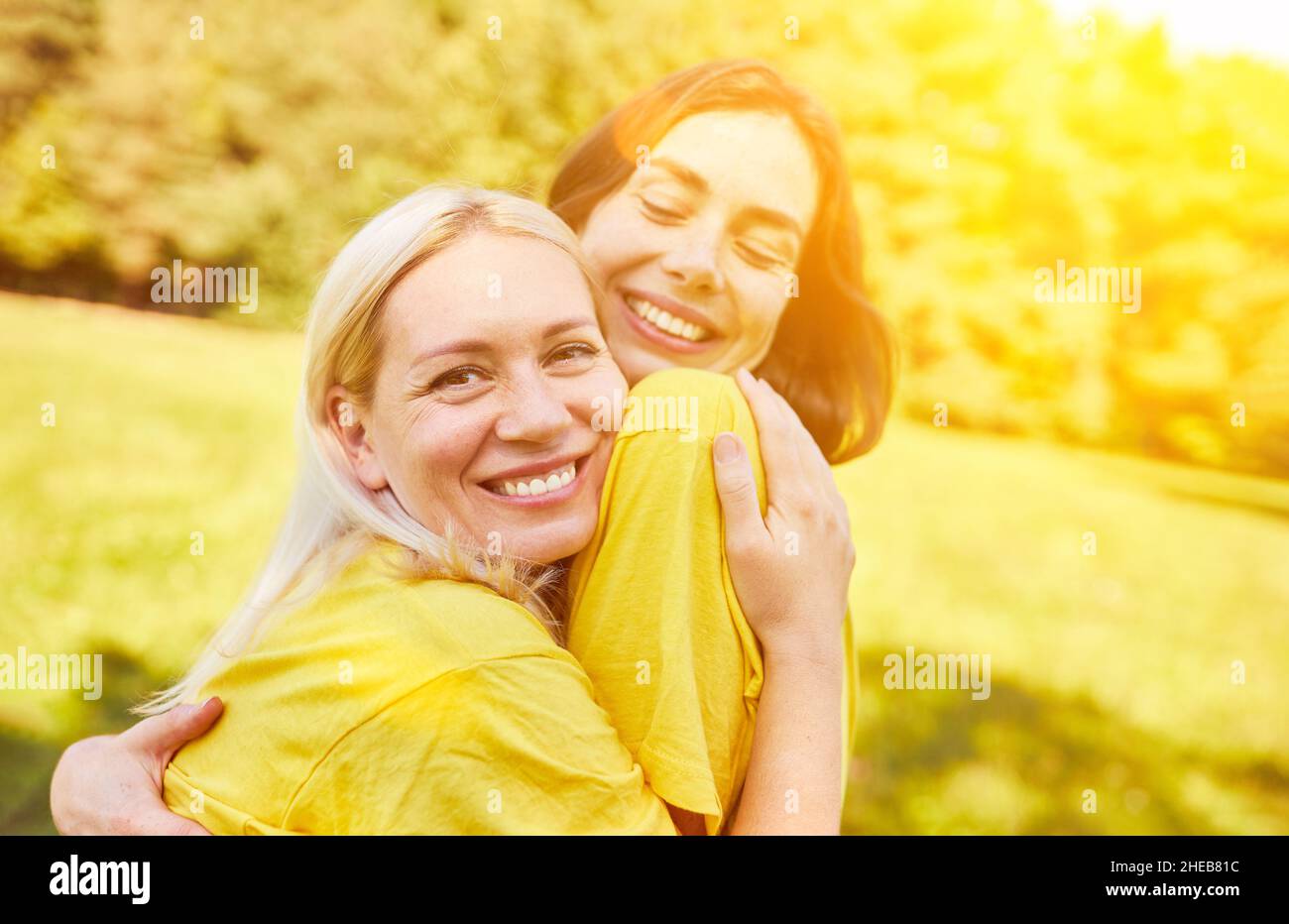 Zwei glückliche junge Frauen umarmen sich im Sommer als Zeichen von Nähe und Freundschaft Stockfoto