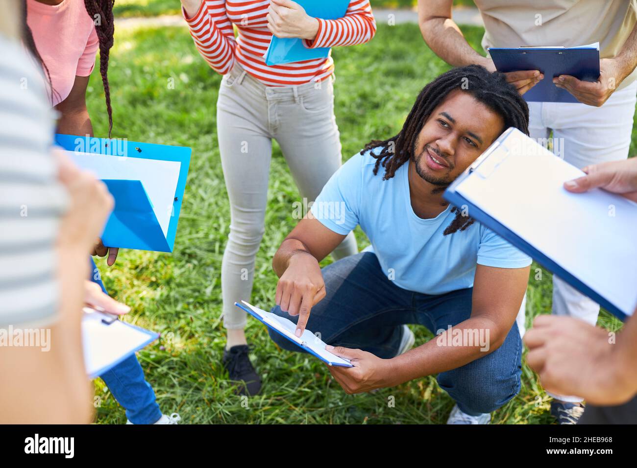 Junger Mann und Freunde diskutieren Strategie für ein Sommerspiel im Park Stockfoto