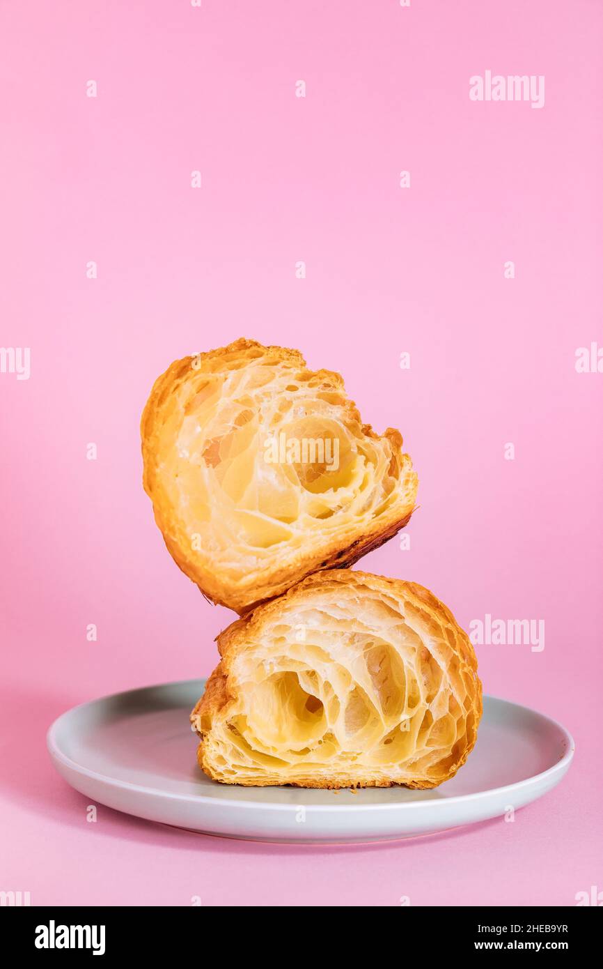 Croissant in zwei Stücke geschnitten isoliert auf violettem Hintergrund. Einfaches und elegantes Konzept. Stockfoto
