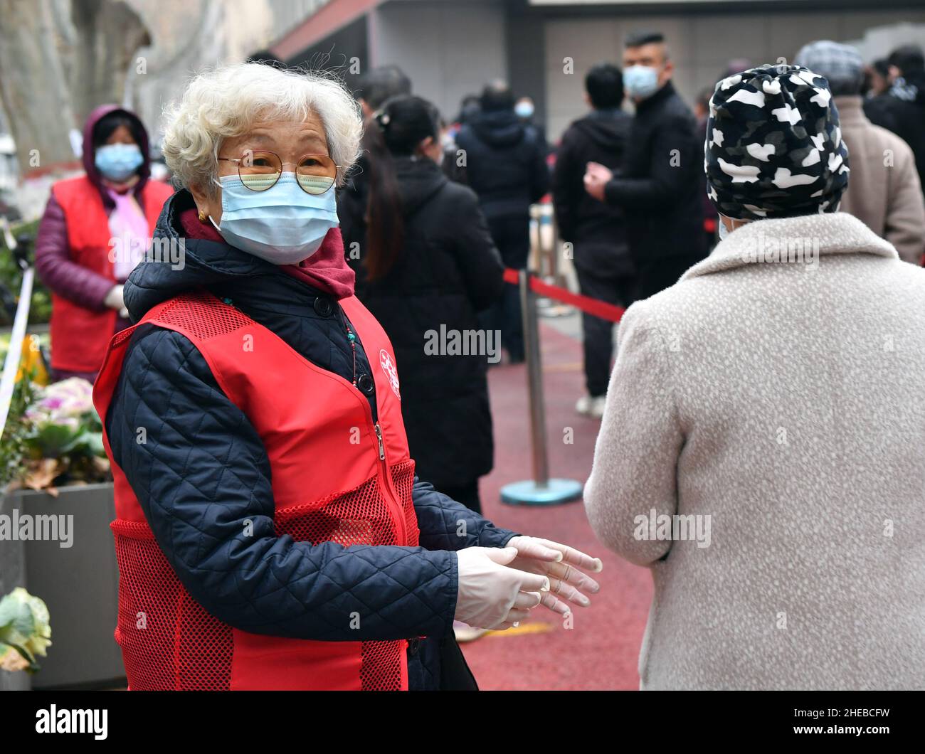 (220110) -- ZHENGZHOU, 10. Januar 2022 (Xinhua) -- der 75-jährige Freiwillige Geng Xiaodi führt Menschen an, sich für COVID-19-Tests an einem Testgelände in Zhengzhou, der zentralchinesischen Provinz Henan, am 7. Januar 2022 zu stellen. Die Stadt hat Rundgänge mit umfassenden Nukleinsäuretests durchgeführt, um die Ausbreitung von COVID-19 einzudämmen. (Xinhua/Li Jianan) Stockfoto