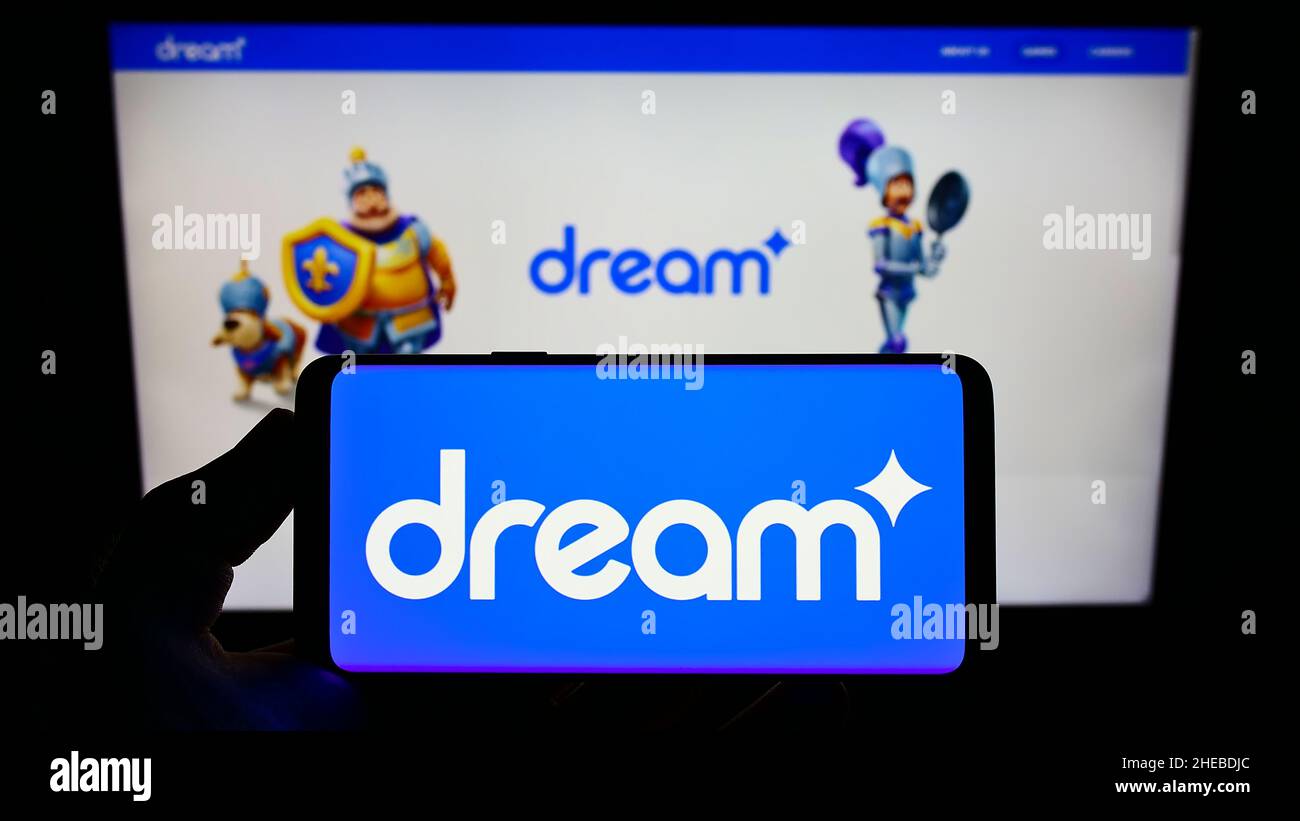 Person, die das Smartphone mit dem Logo des türkischen Spieleunternehmens Dream Games auf dem Bildschirm vor der Website hält. Konzentrieren Sie sich auf die Telefonanzeige. Stockfoto